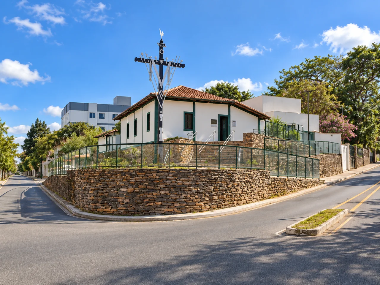 Edificação histórica com cruzeiro e muros de pedra.